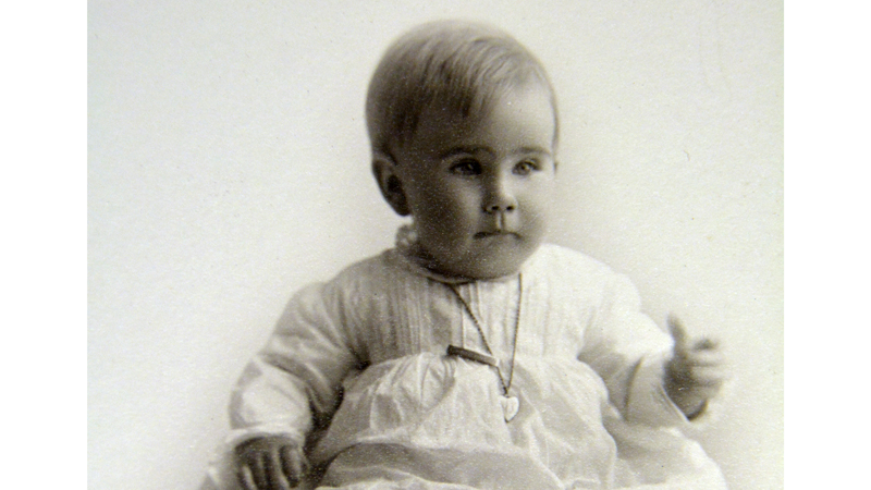 A vintage photo of a baby in a white christening gown